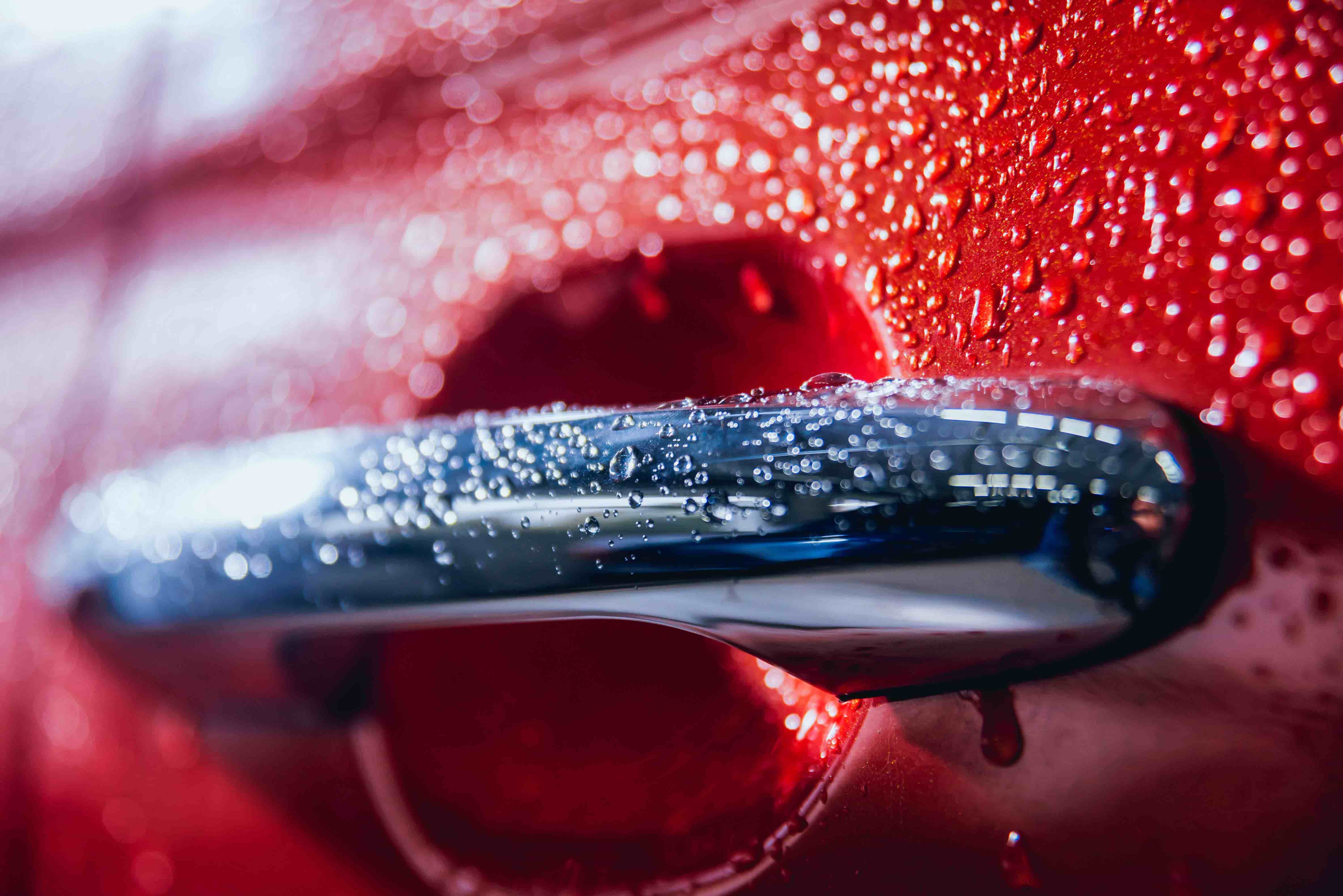 Close-up detail of electric car door handle with rain drops showcasing precision car detailing and attention to detail